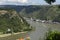 Loreley, Germany - 25 July 2021. A large barge carrying a lot of containers on the Rhine River in western Germany, visible hills o