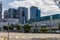 The Los Angeles Convention Center with lush green trees, office buildings and skyscrapers in the city skyline and cars