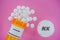 Losartan Rx medicine pills in plactic vial with tablets. Pills spilling from yellow container on pink background