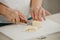 Ð¡lose photo of the hands of woman who is cutting butter on a board with a knife