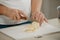 Ð¡lose photo of the hands of woman who is cutting butter on a board with a knife