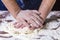 Ð¡lose up of chef human`s hands kneading the dough on the table, powdering with flour. Making dough by hands at bakery or at home