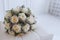 Ð¡lose-up of a wedding bouquet of cream roses with purple flowers lies on a white sofa