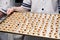 Ð¡loseup of pastry chef in uniform at restaurant professional kitchen holding baking tray with small round sand cookies with