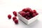 Ð¡loseup of pile of ripe raspberries, white square bowl full of juicy raspberries