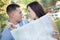 Lost and Confused Mixed Race Couple Looking Over Map Outside