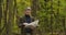 Lost gray-haired Caucasian tourist standing in the autumn forest and looking at the map. Disorientated man searching the