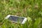 Lost smartphone lies in green grass on a spring day