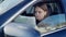 Lost troubled Caucasian young woman sitting on driver's seat in car examining paper map. Portrait of anxious worried