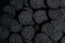 A lot of black cookies with a white cream center on a black canvas background in dark colors.