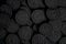 A lot of black cookies with a white cream center on a black canvas background in dark colors.