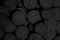 A lot of black cookies with a white cream center on a black canvas background in dark colors.