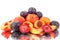 A lot of bright fruits, whole and cut peaches and plums on a mirror white background in water drops isolated