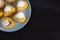A lot of buns on a blue round plate on a black background in the corner of the table