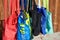 Lot of colorful eco-friendly reusable cloth bags hanging on a pole near a wooden fence