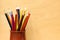 A lot of colorful sharpened pencils are in the cup on the wooden background