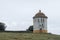 A lot of common pigeons on the roof of a round, large and old dovecote in the pasture of Extremadura