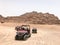 A lot of four-wheeled multicolored powerful fast off-road four-wheel drive buggies, cars, SUVs in the sandy hot desert on the sand