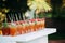 A lot of glasses with a straw with natural juice on the table. An open-air party. Homemade compote decorated with cherries and