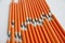 A lot of orange pencils in a row over a table.