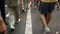 A lot of people feet of variety pedestrians crowd, people active walking on crowded street on pavement. Legs shoes