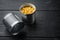 Lot of pieces of canned yellow corn in metall can, on black wooden table background with copy space for text