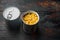Lot of pieces of canned yellow corn in metall can, on old dark  wooden table background