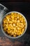 Lot of pieces of canned yellow corn in metall can, on old dark  wooden table background, top view flat lay