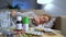 A Lot Of Pills And Medicines On A Table In Front Of A Sick Young Woman On Couch