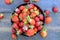 Lot of ripe appetizing strawberries in the round bowl on vintage wooden table closeup