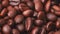 A lot of roasted coffe beans, close shot. Dolly shot of heap of brown coffee beans, abstract background. Selective soft