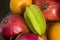 A lot of tropical fruits in a glass vase. Exotic fruits: averrhoa carambola, Pitahaya, Mango, tangerines, pomegranate fruit