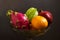 A lot of tropical fruits in a glass vase. Exotic fruits: averrhoa carambola, Pitahaya, tangerines, pomegranate fruit. Gray