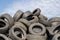 A lot of used tyres against blue sky with white clouds