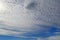 A lot of white clouds of different types: cumulus, cirrus, layered high in blue sky