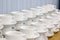 Lot of white porcelain tea pairs in piles in a straight line. Co