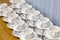 Lot of white porcelain tea pairs in piles in a straight line. Co