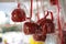 Lots of appetizing red candied apples hanging outdoors.