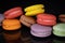 Lots of colorful macaroons on black background with reflection. Traditional french dessert