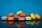 Lots of colorful macaroons on blue background with reflection. Traditional french dessert