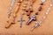 Lots of different styled Christian crosses, multiple rosaries laying on brown background Prayer and belief, christianity symbols