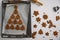 Lots of gingerbread cookies are laid out in shape of Christmas tree on parchment