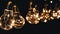 Lots Hanging Swinging Glowing Vintage Edison Light Bulbs on Black Background