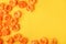 Lots of orange artificial flowers on a yellow background. Flat layout with space for text