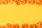 Lots of orange artificial flowers on a yellow background. Flat layout with space for text