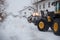 Lots of snow on the street. tractor clears the snow with the loader