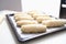 Lots of uncooked puff pastry buns on baking sheet closeup