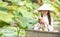 A lotus flower in the hand of a Vietnamese woman. Beautiful Vietnamese holding Pink Lotus on wooden boat in the lake vietnam