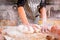 Ð¡loud of white flour flying into air as a woman chef energetically kneads dough on the kitchen table.