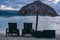 Lounge chairs and a straw thatch roof umbrella by the beach